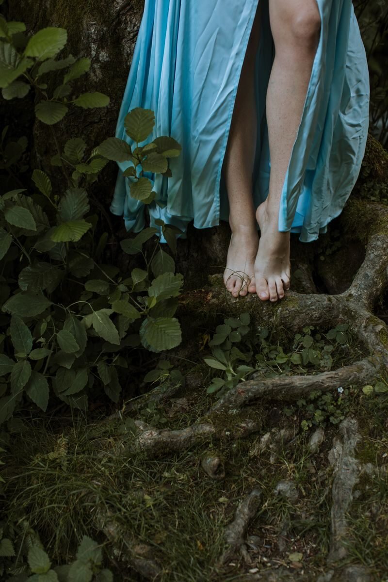 Captivating image showcasing bare feet and a flowing dress amidst lush forest foliage.